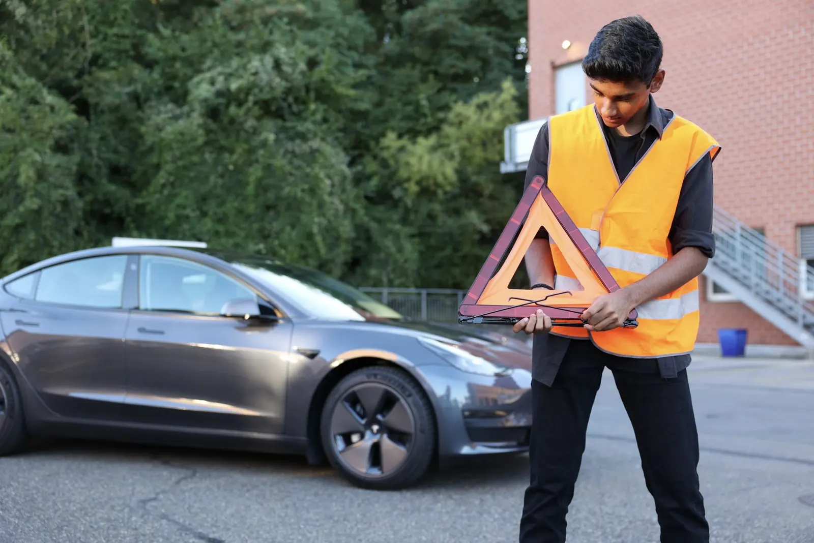 Fahrschüler stellt mit Warnweste das Pannendreieck auf